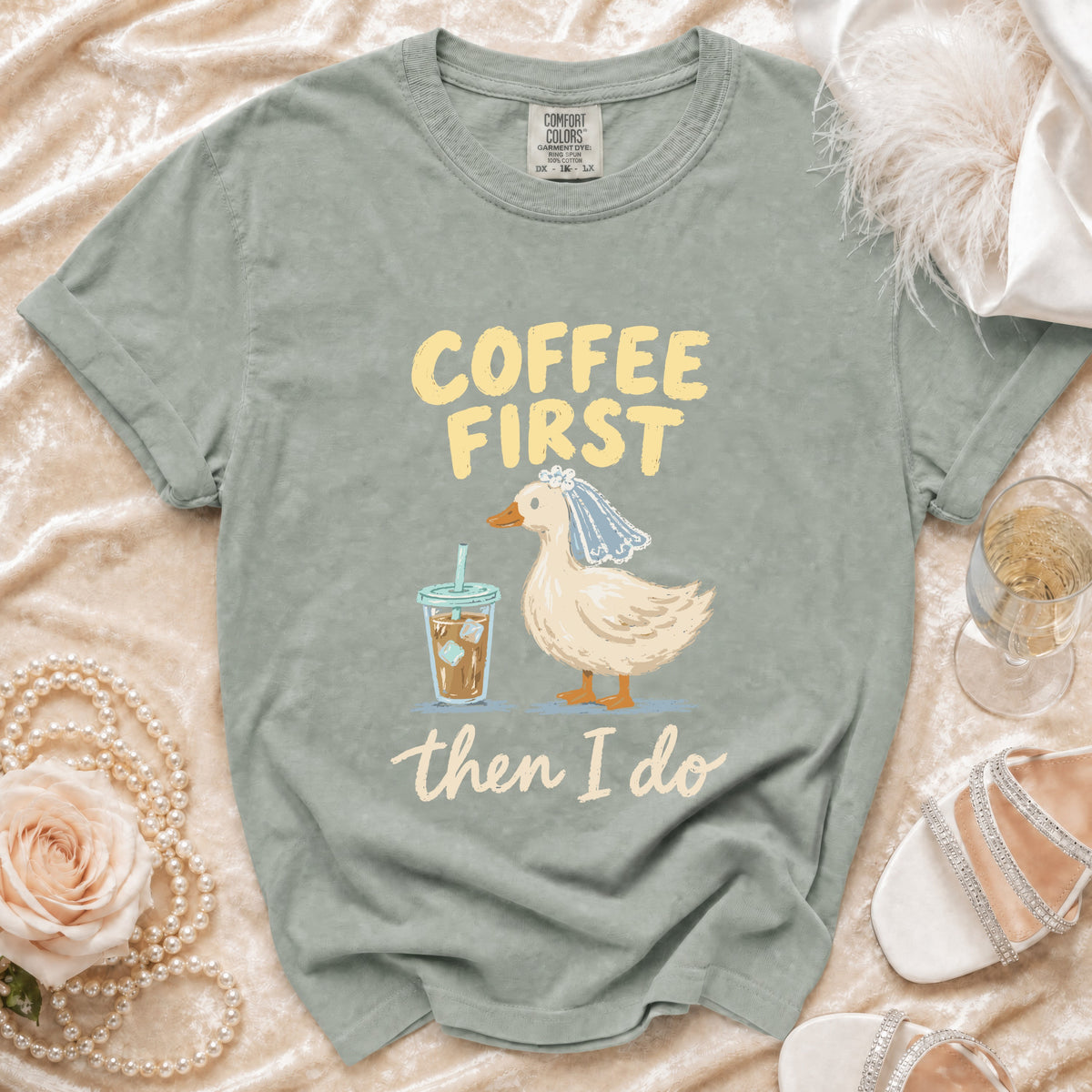 T-shirt with a duck wearing a veil and drinking coffee, text reads "Coffee First then I do."
