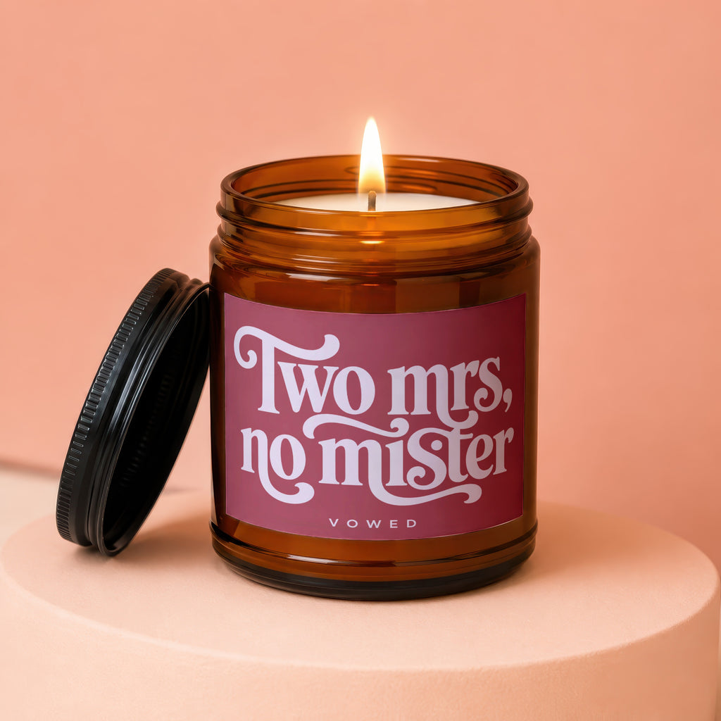 Amber jar candle with lit wick, reading "Two Mrs, no Mister" and "vowed."
