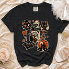 Black t-shirt with various Halloween-themed graphic stickers including cats, skeletons, and a haunted house.