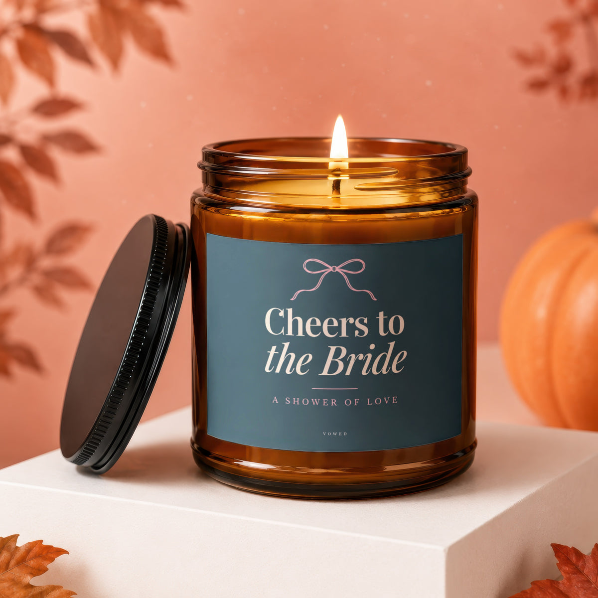 Lit candle in amber jar with "Cheers to the Bride" label and bow.