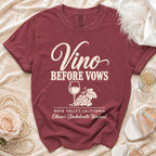 Maroon t-shirt with cream text reading "Vino BEFORE VOWS," a wine glass, grapes, and "Napa Valley, California."
