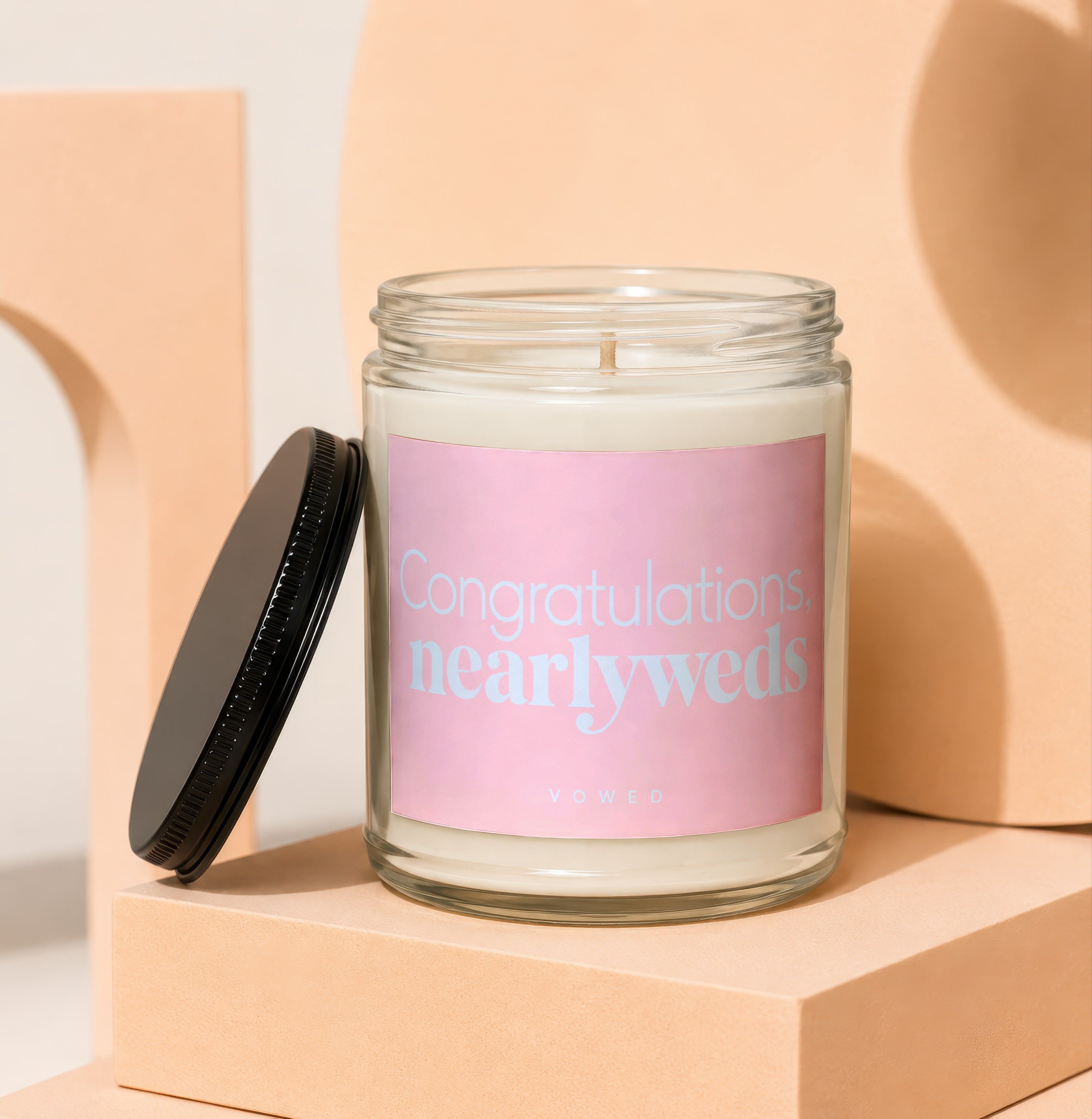 Glass jar candle with pink label reading "Congratulations, newlyweds" and "vowed."