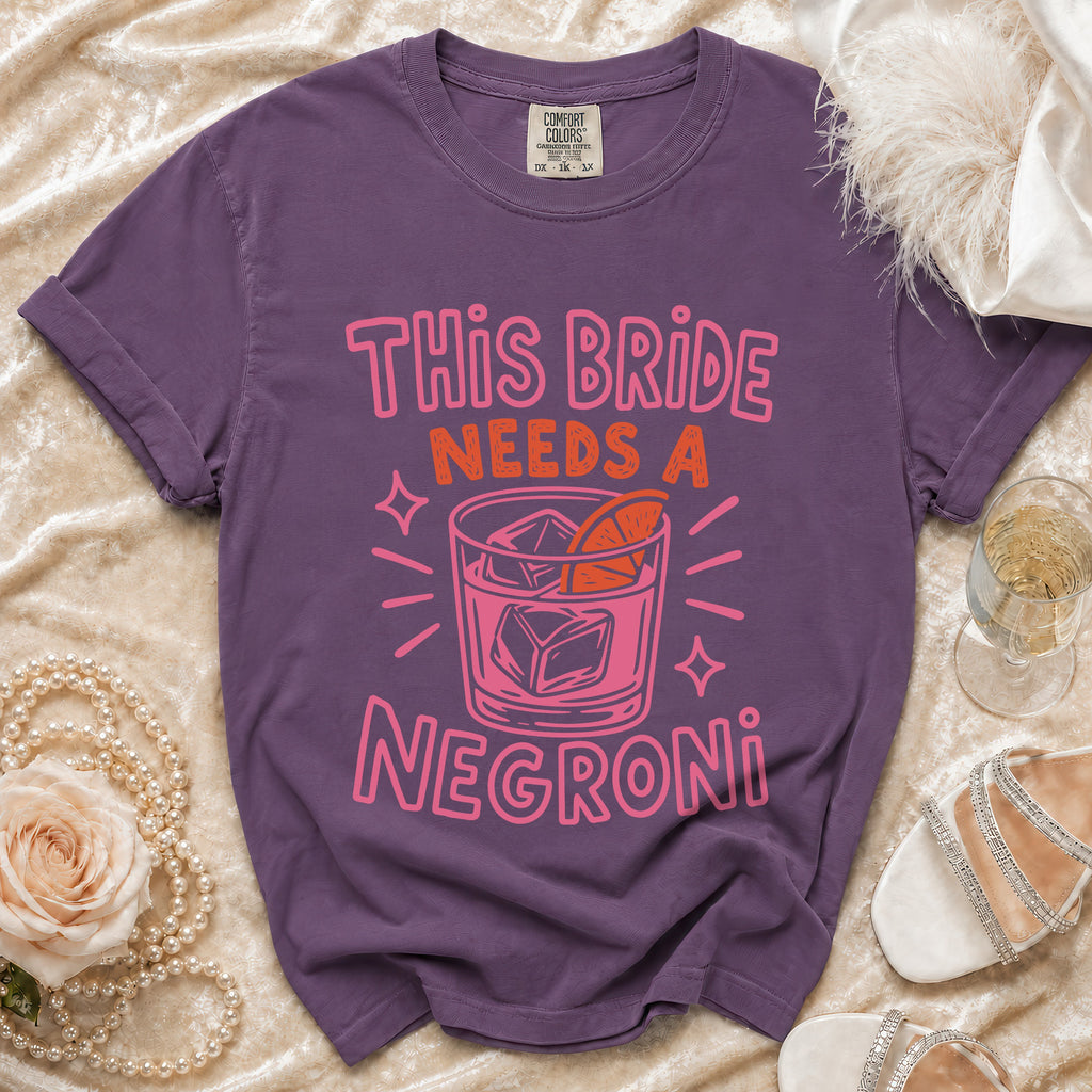 Purple t-shirt with pink text "This Bride Needs a Negroni" and a cocktail illustration.