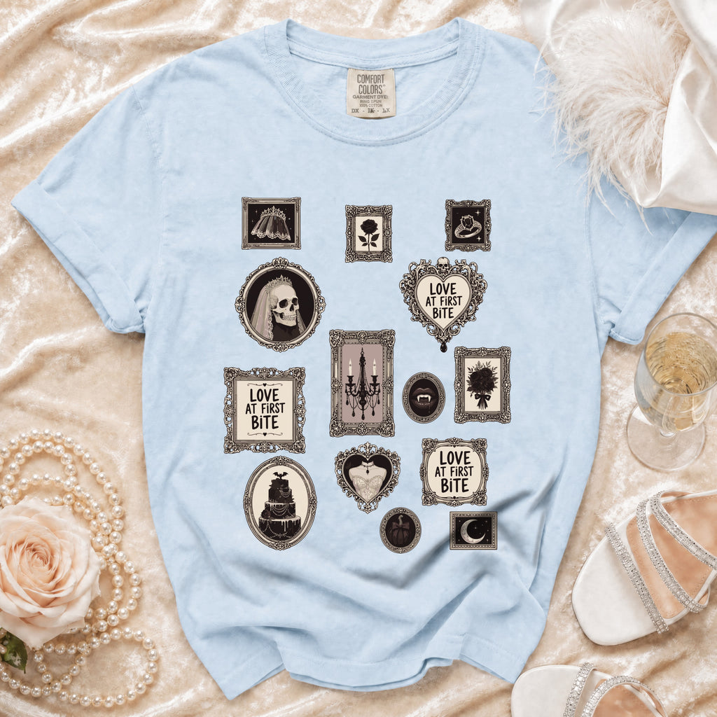 Light blue t-shirt with gothic-themed framed graphics including skulls, bats, and text.