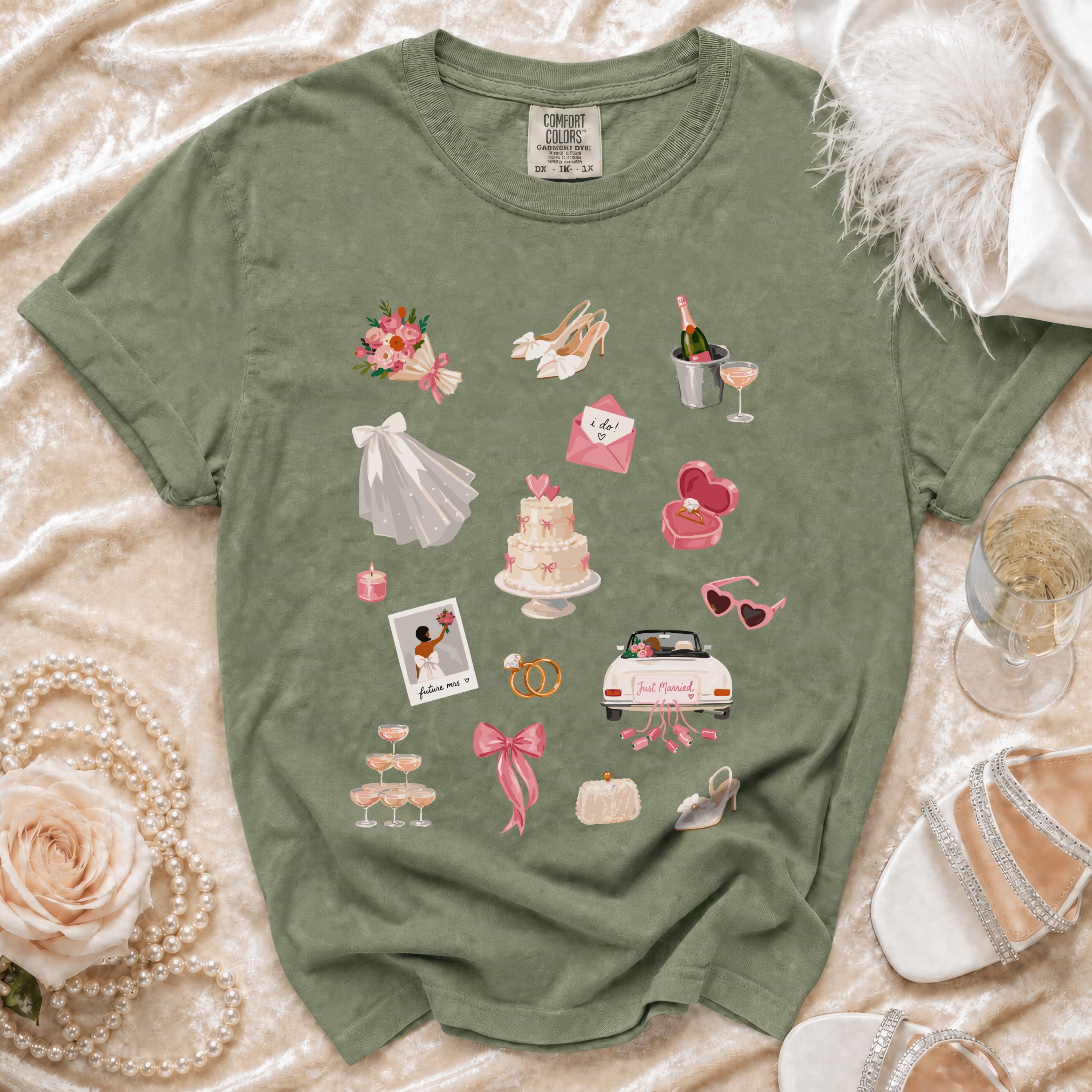 Green t-shirt with watercolor wedding graphics: bouquet, cake, rings, car, shoes, and champagne.