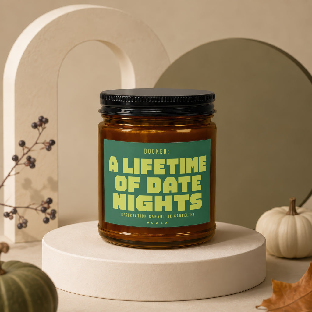 Amber candle with green label reading "BOOKED: A LIFETIME OF DATE NIGHTS RESERVATION CANNOT BE CANCELLED VOWED".