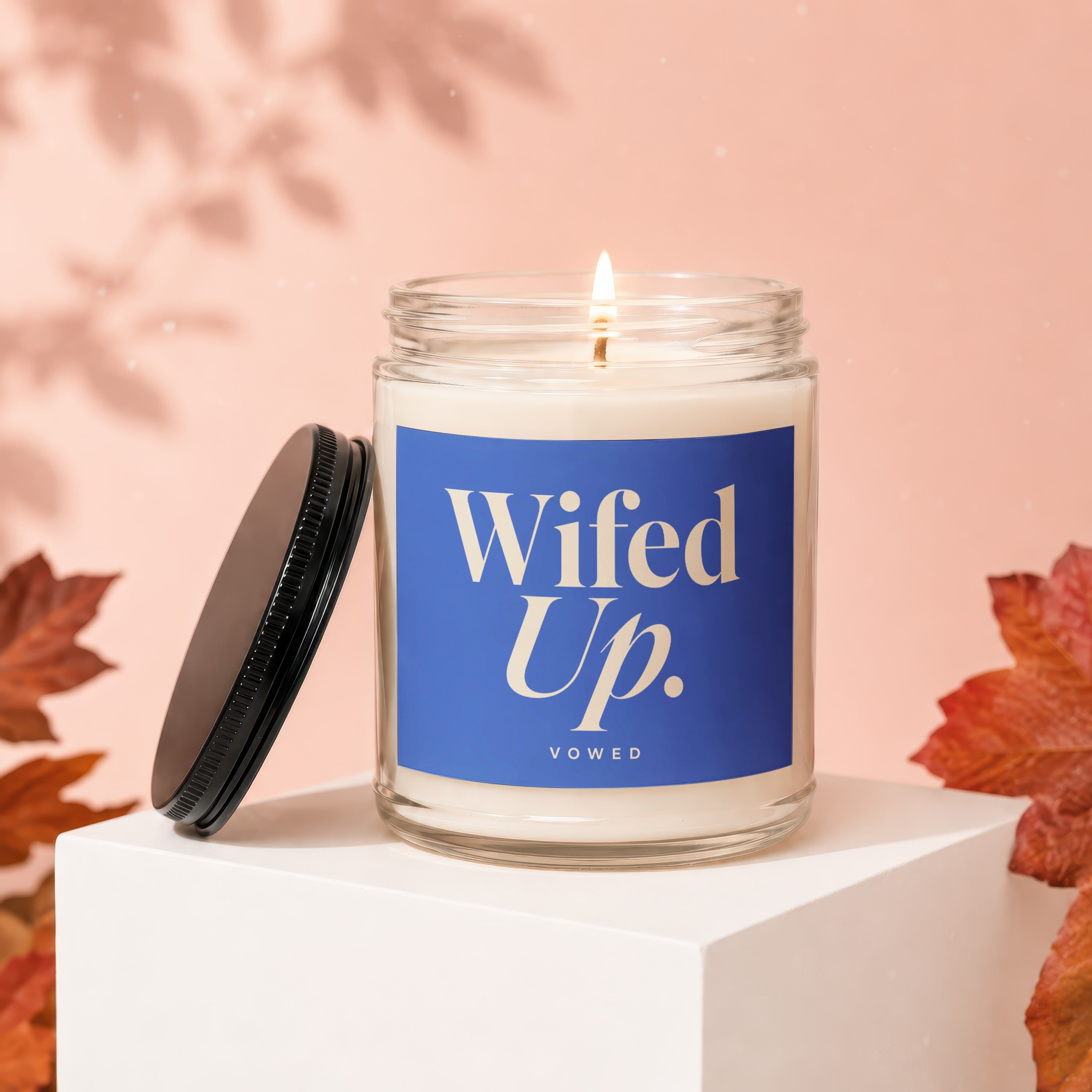 Candle with "Wifed Up. VOWED" text on blue label, with lid off.