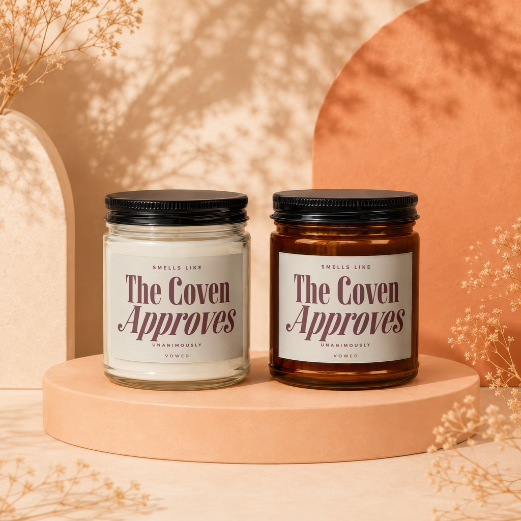 Two candles labeled "The Coven Approves" sit on pedestals with dried flowers.