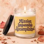 Lit candle in glass jar with yellow label saying "Mission Impossible Accomplished VOWED".