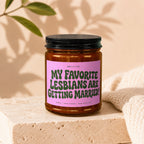 Amber jar candle with pink label reading "MY FAVORITE LESBIANS ARE GETTING MARRIED!"
