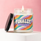 Glass jar candle with colorful wavy stripe label reading "FINALLY! WE CALLED IT ON DATE THREE VOWED".
