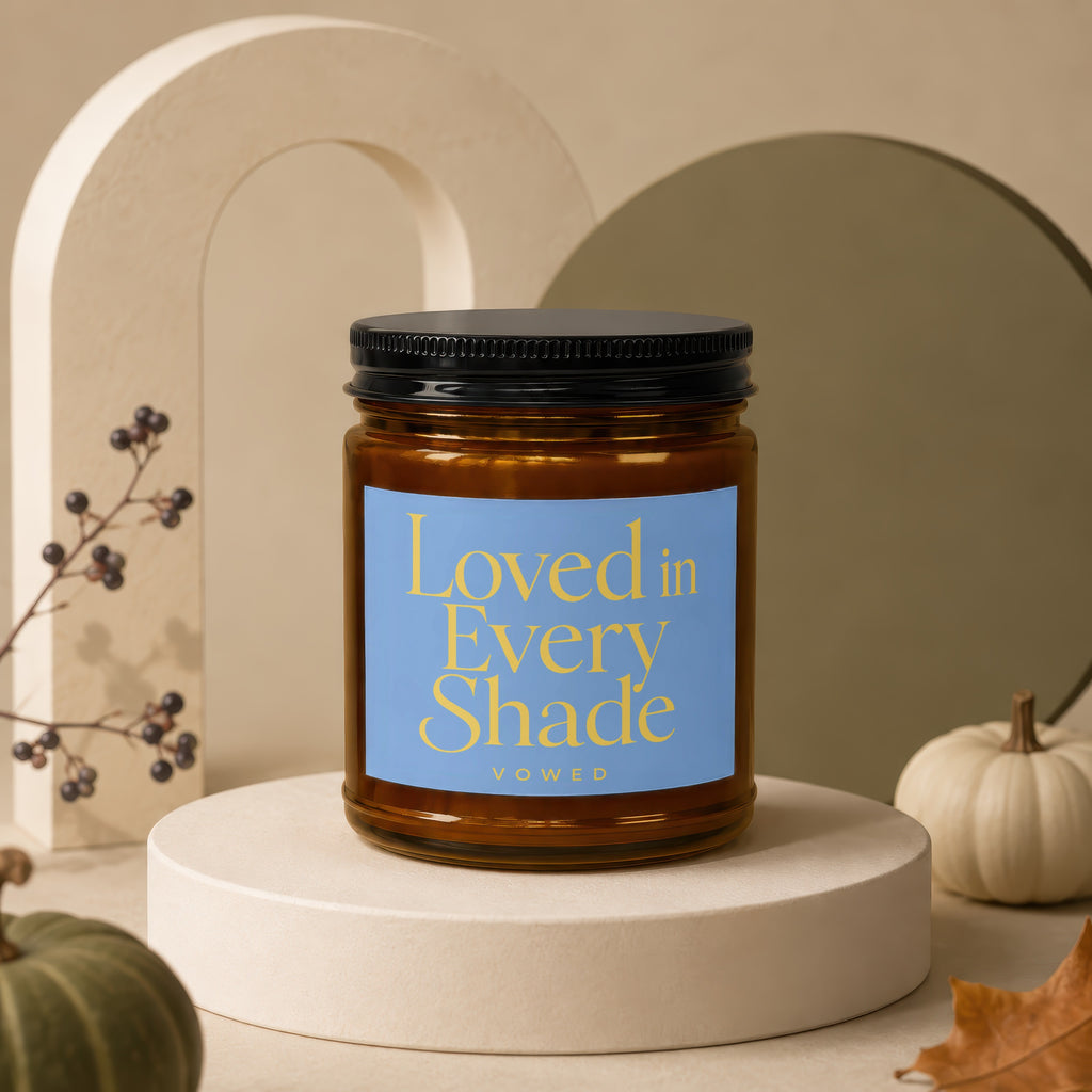Glass candle with black lid and blue label that reads "Loved in Every Shade Vowed"