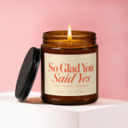 Amber glass candle with lit wick, label reads "So Glad You Said Yes".