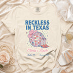 Cream t-shirt with "Reckless in Texas" and "Olivia's Bach" text, cowboy boots, and hat.