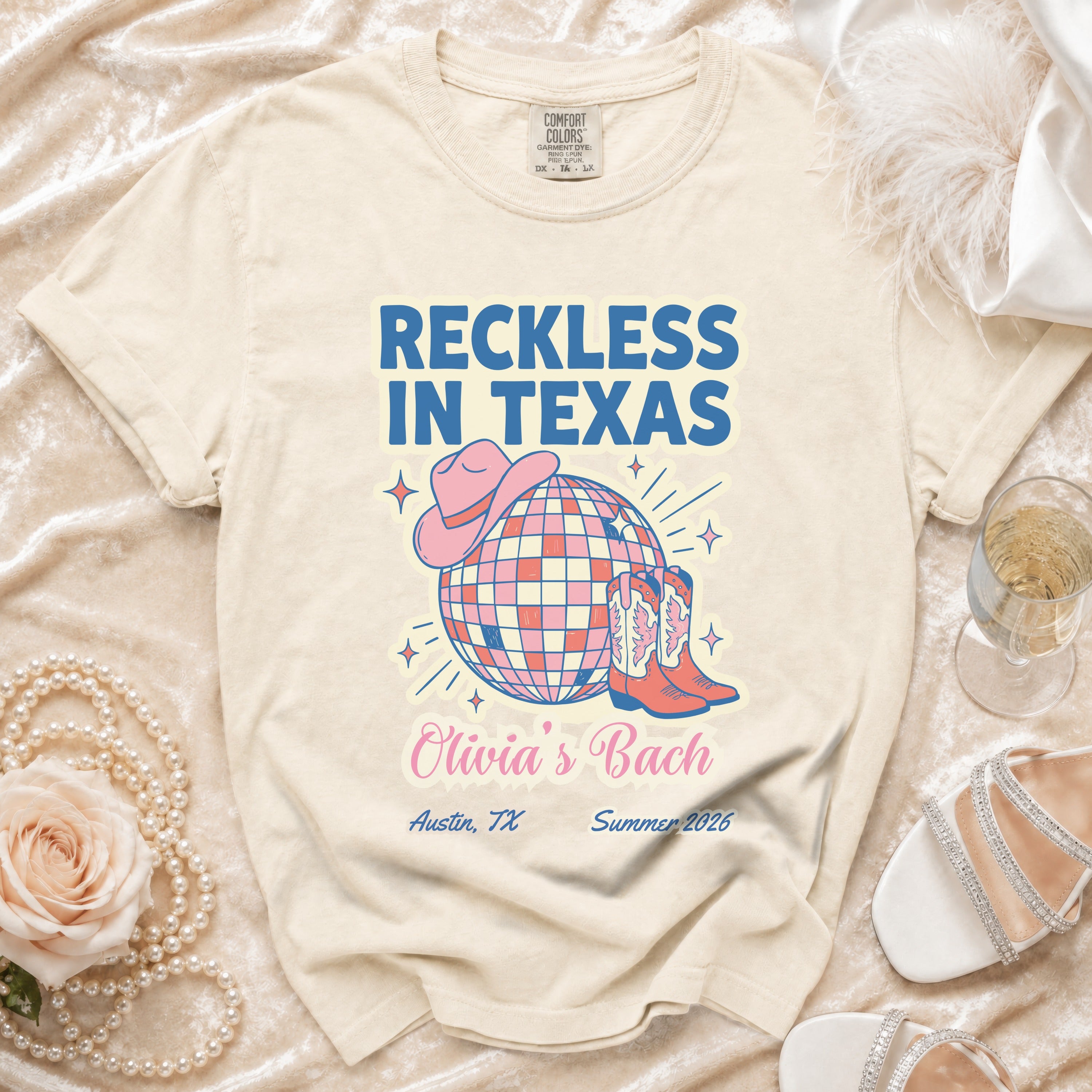 Cream t-shirt with "Reckless in Texas" and "Olivia's Bach" text, cowboy boots, and hat.