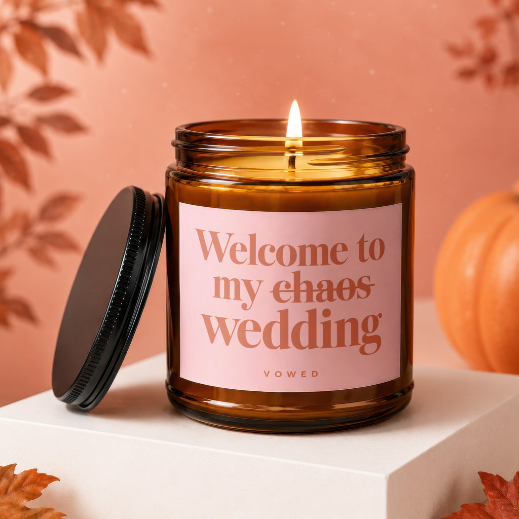 Amber jar candle with pink label reading "Welcome to my chaos wedding VOWED".