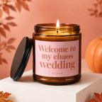 Amber jar candle with pink label reading "Welcome to my chaos wedding VOWED".