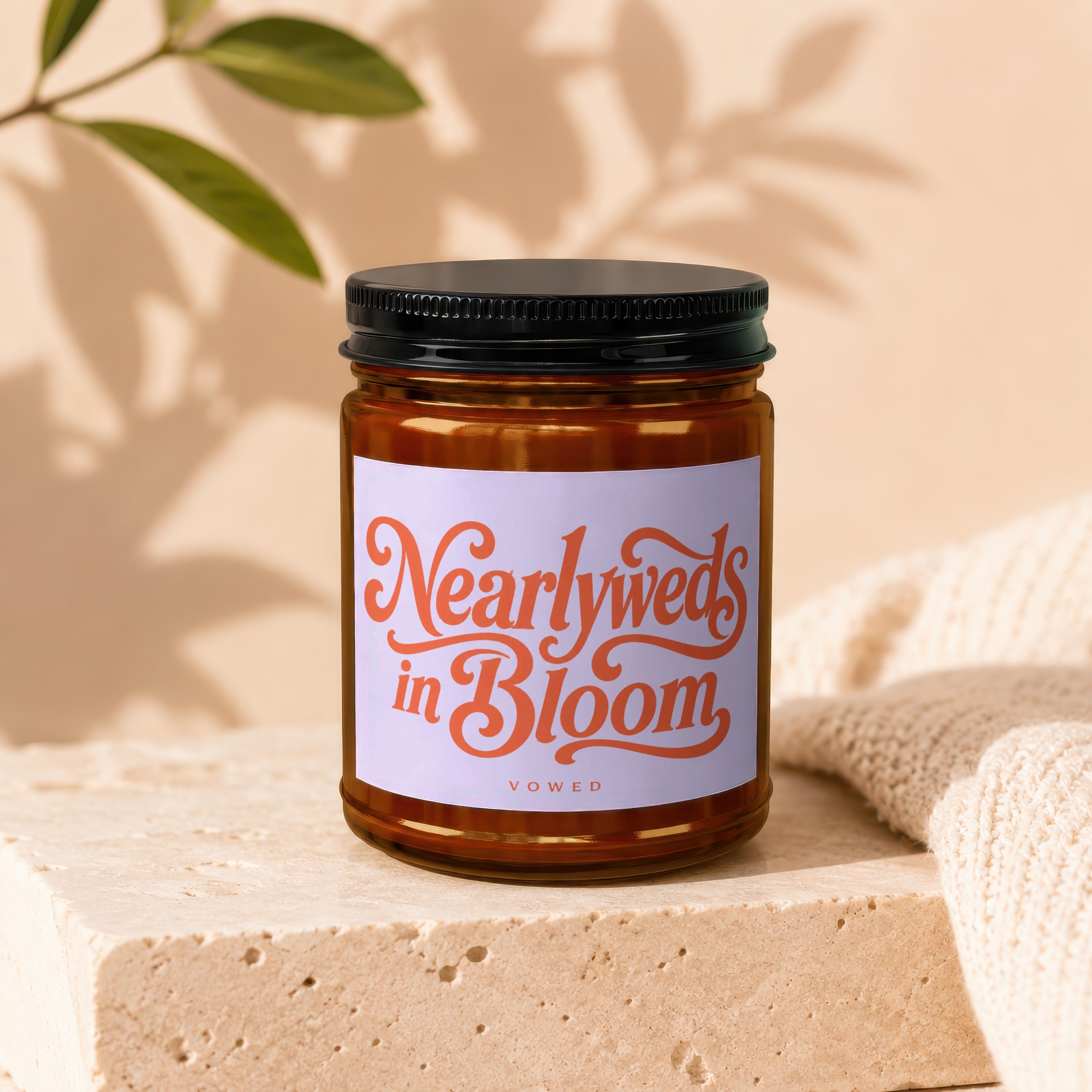 Brown glass candle with black lid, label reads "Nearlyweds in Bloom."