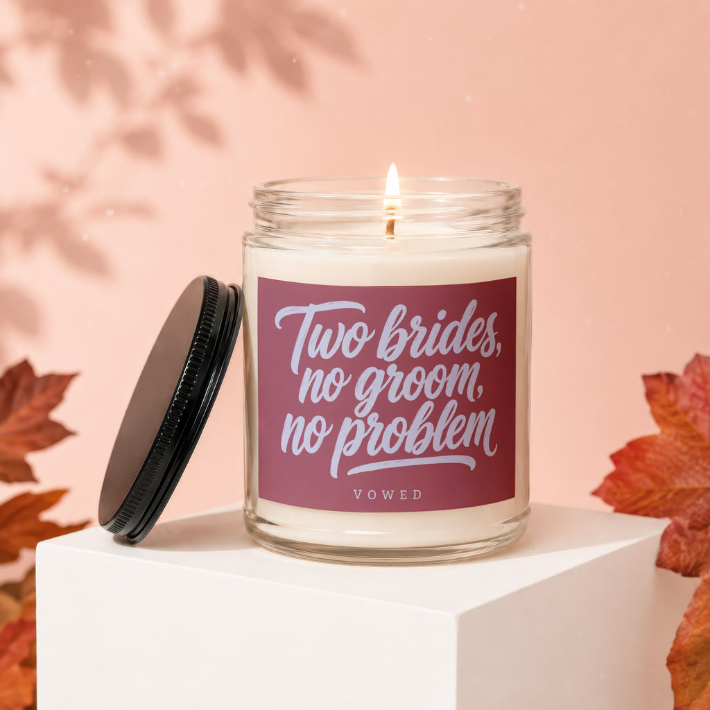 Glass candle with "Two brides, no groom, no problem" text and a lit wick.