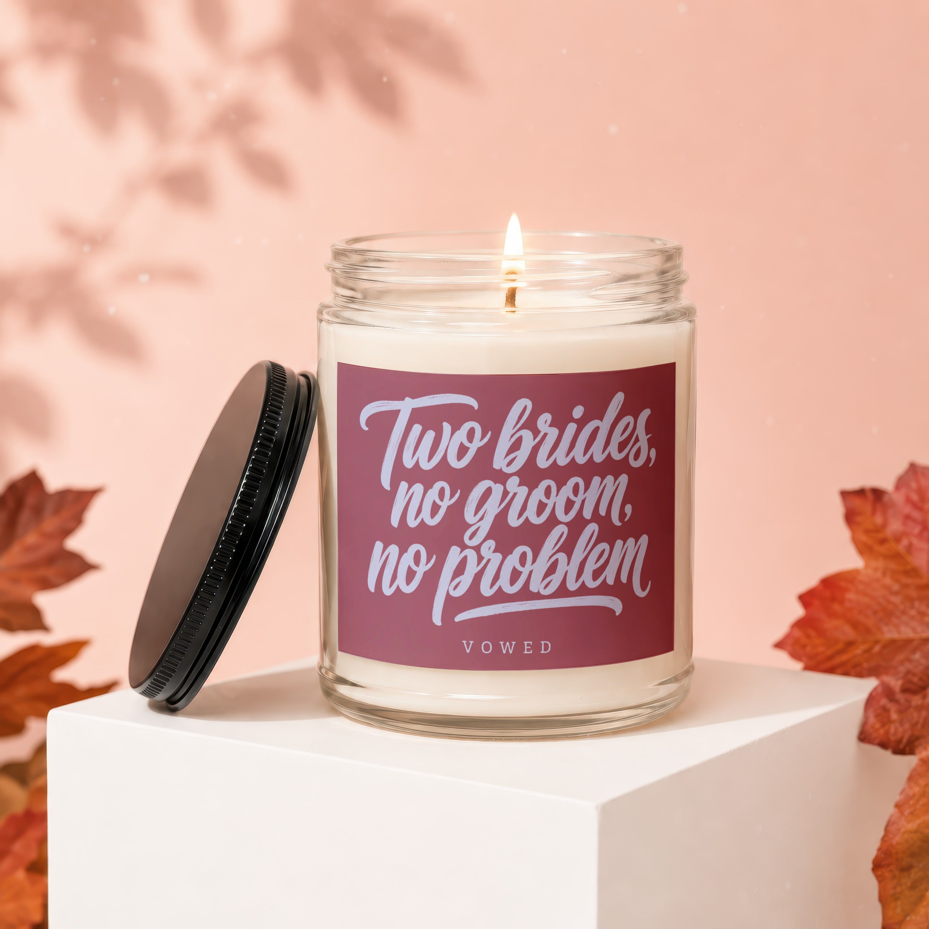 Glass candle with "Two brides, no groom, no problem" text and a lit wick.