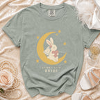 Sage t-shirt with a graphic of a bunny on a moon holding a heart, with text "STARRY-EYED BRIDE".