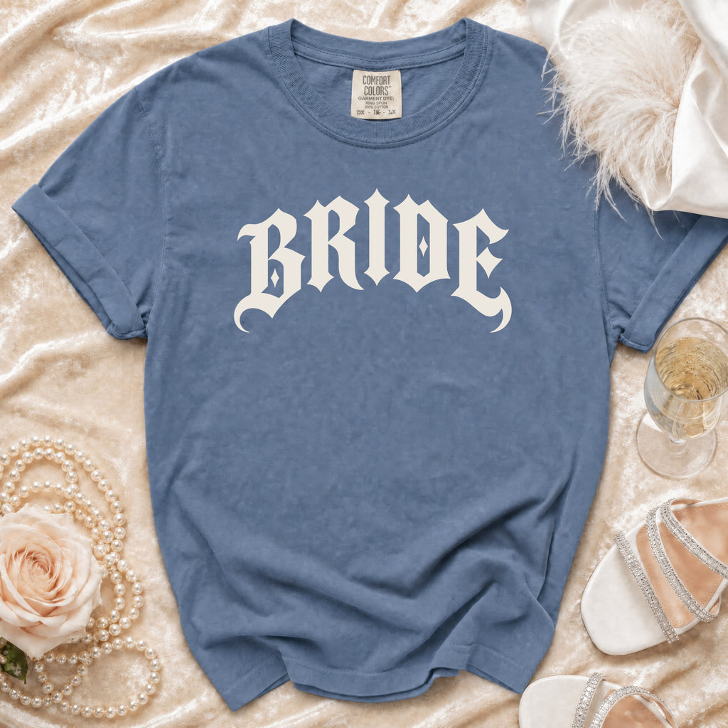 Blue t-shirt with white gothic font "BRIDE" text, surrounded by wedding accessories.