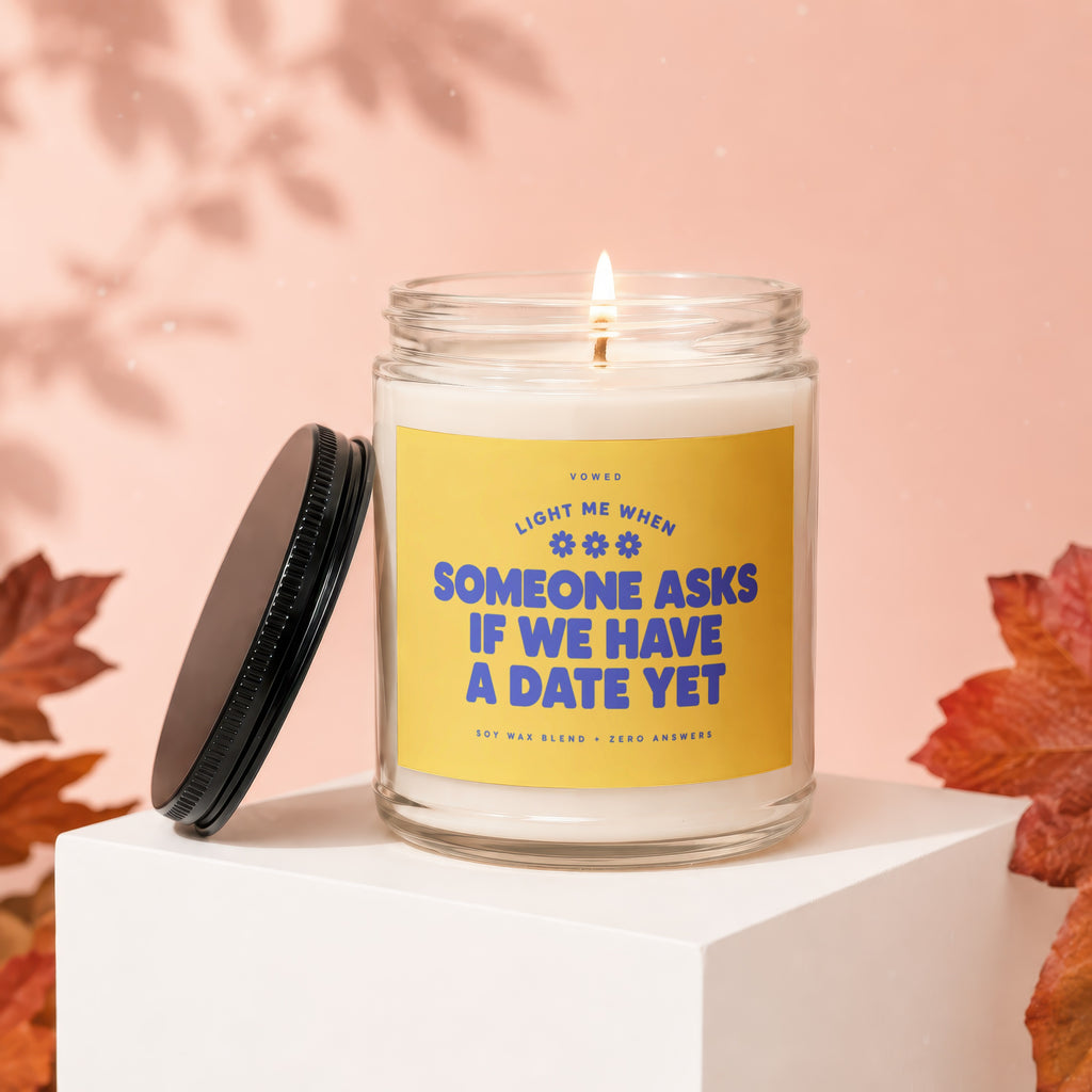 Candle with yellow label reading "Light me when someone asks if we have a date yet."