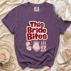 Purple t-shirt with "This Bride Bites" graphic and wedding-themed icons.