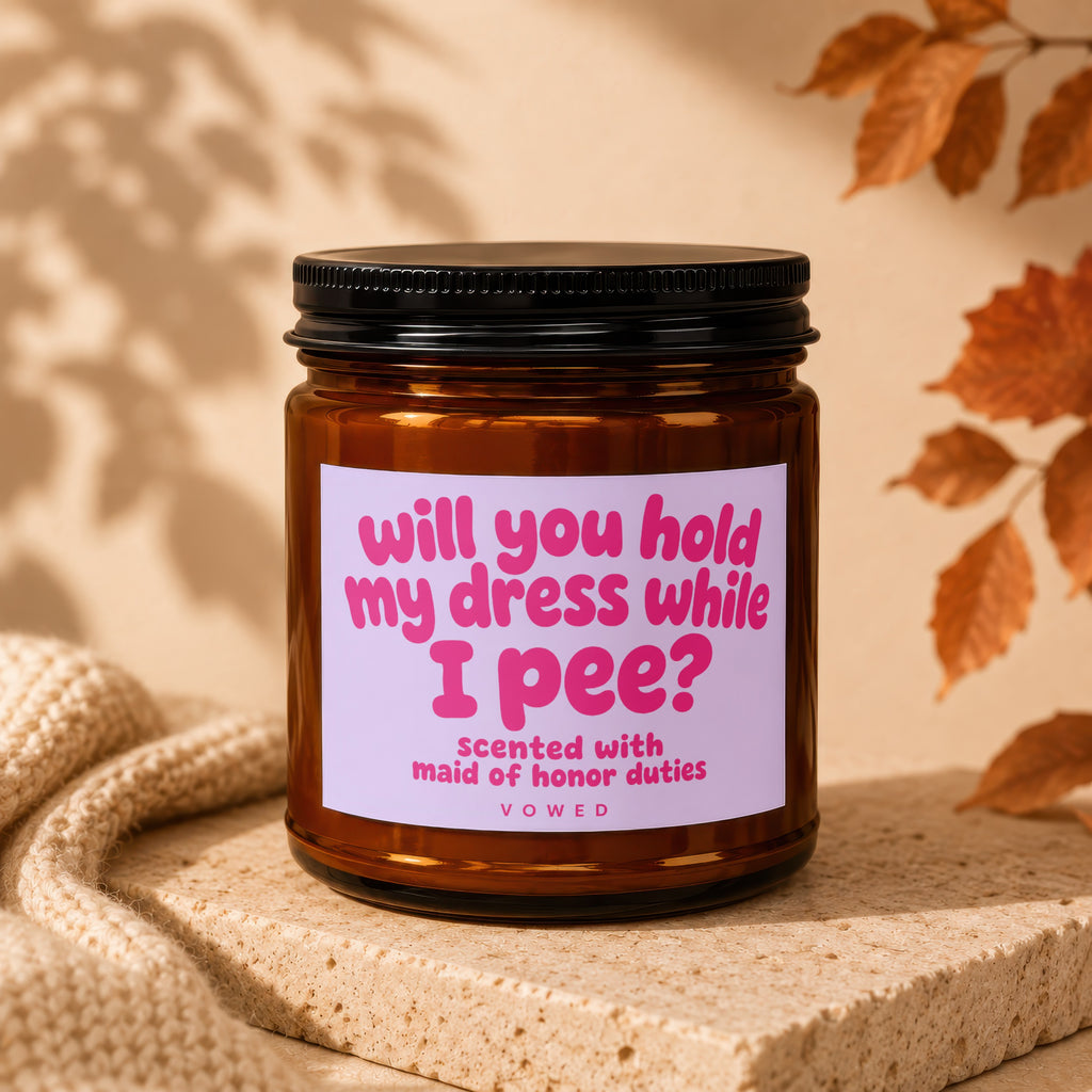 Amber jar candle with pink text "Will you hold my dress while I pee?"
