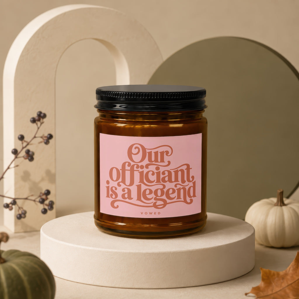 Amber candle with a pink label that reads "Our officiant is a legend" and "vowed".
