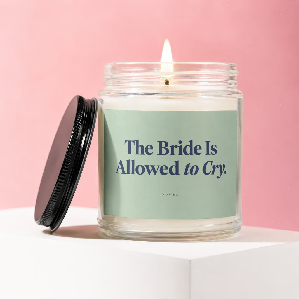 Candle with a lit wick and "The Bride Is Allowed to Cry." text on a light green label.