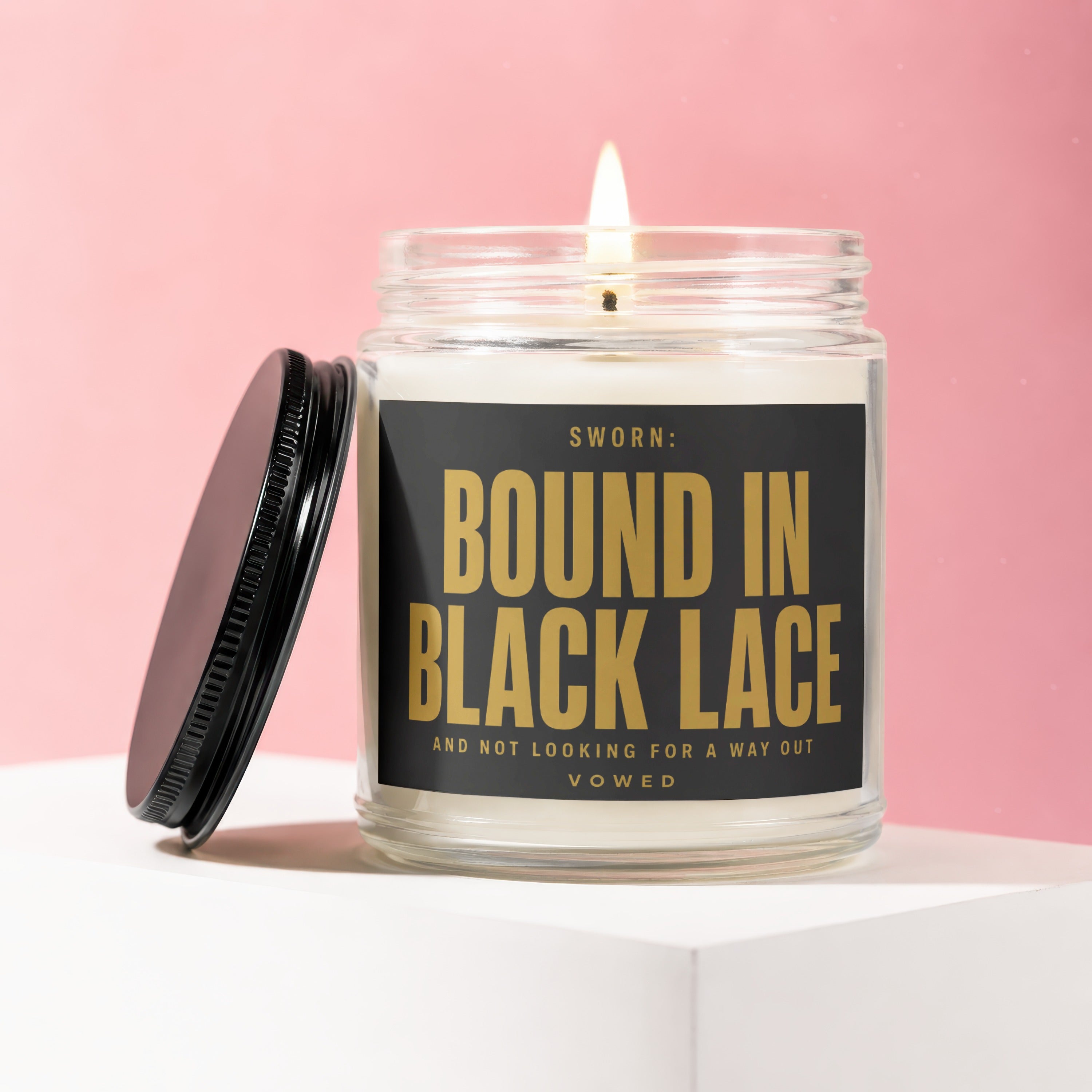 Glass candle with black lid and label reading "SWORN: BOUND IN BLACK LACE AND NOT LOOKING FOR A WAY OUT VOWED."
