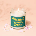Glass jar candle with lit wick and teal label reading "Married. Iconic. Done. VOWED."