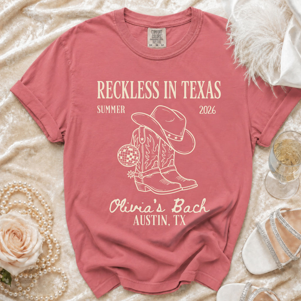 Rose quartz t-shirt with cowboy boots, hat, disco ball, and "Reckless in Texas" text.
