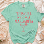 Teal t-shirt with pink text "This Girl Needs a Margarita" and margarita graphic.
