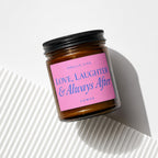 Brown glass candle with pink label reading "Smells Like Love, Laughter & Always After".