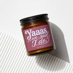 Brown glass candle with a maroon label that reads "Yaaas we said I do"