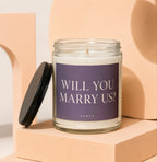 Glass candle with purple label that reads "WILL YOU MARRY US? VOWED".