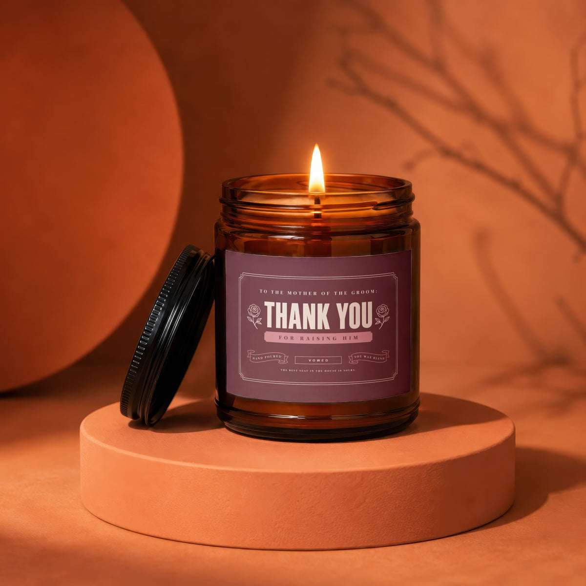 Amber jar candle with "Thank You for Raising Him" label, lit flame.