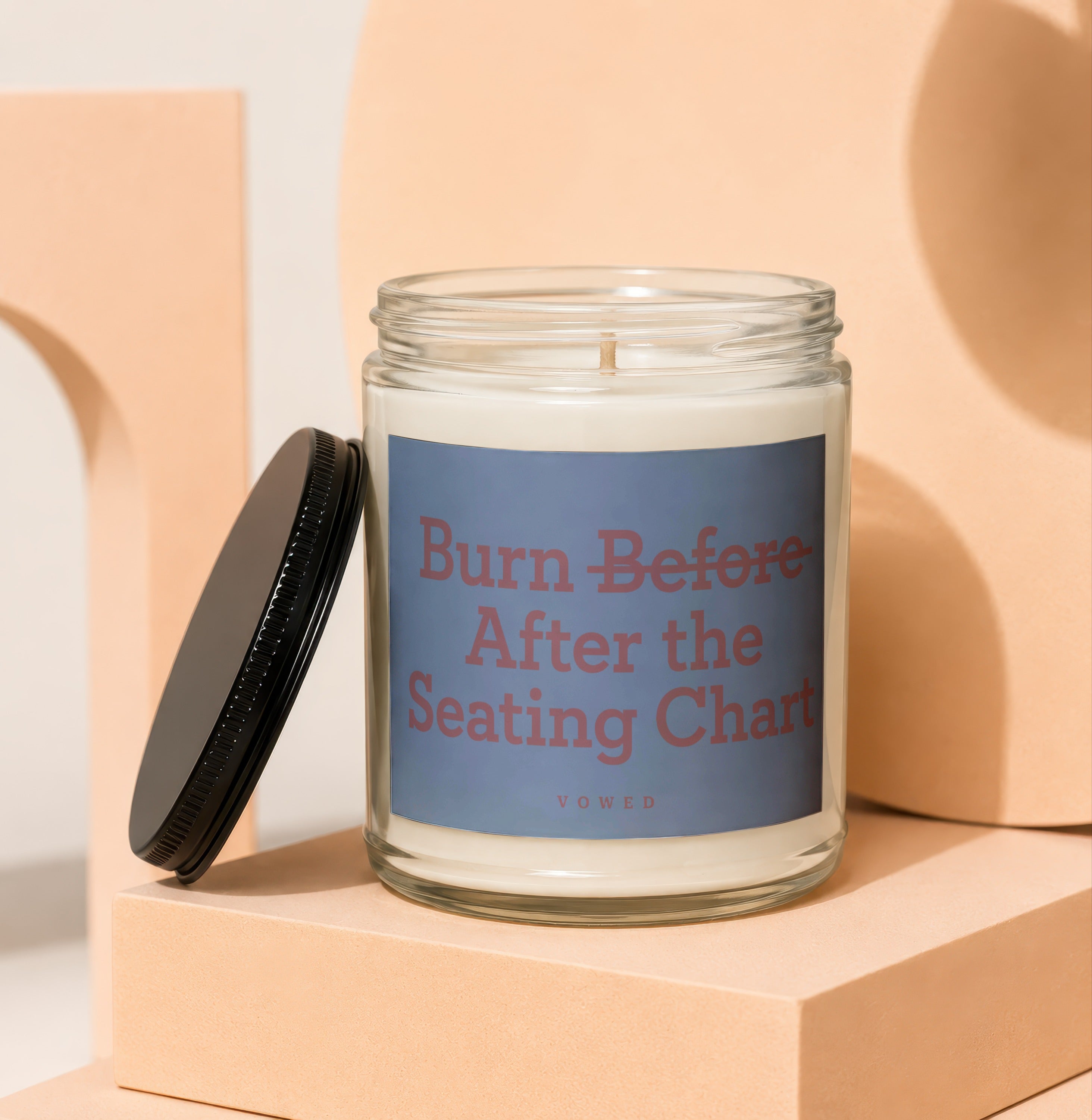 Glass candle with "Burn Before After the Seating Chart" text and small "vowed" label.