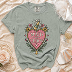 Light green t-shirt with pink heart graphic that says "MAID OF CHAOS".