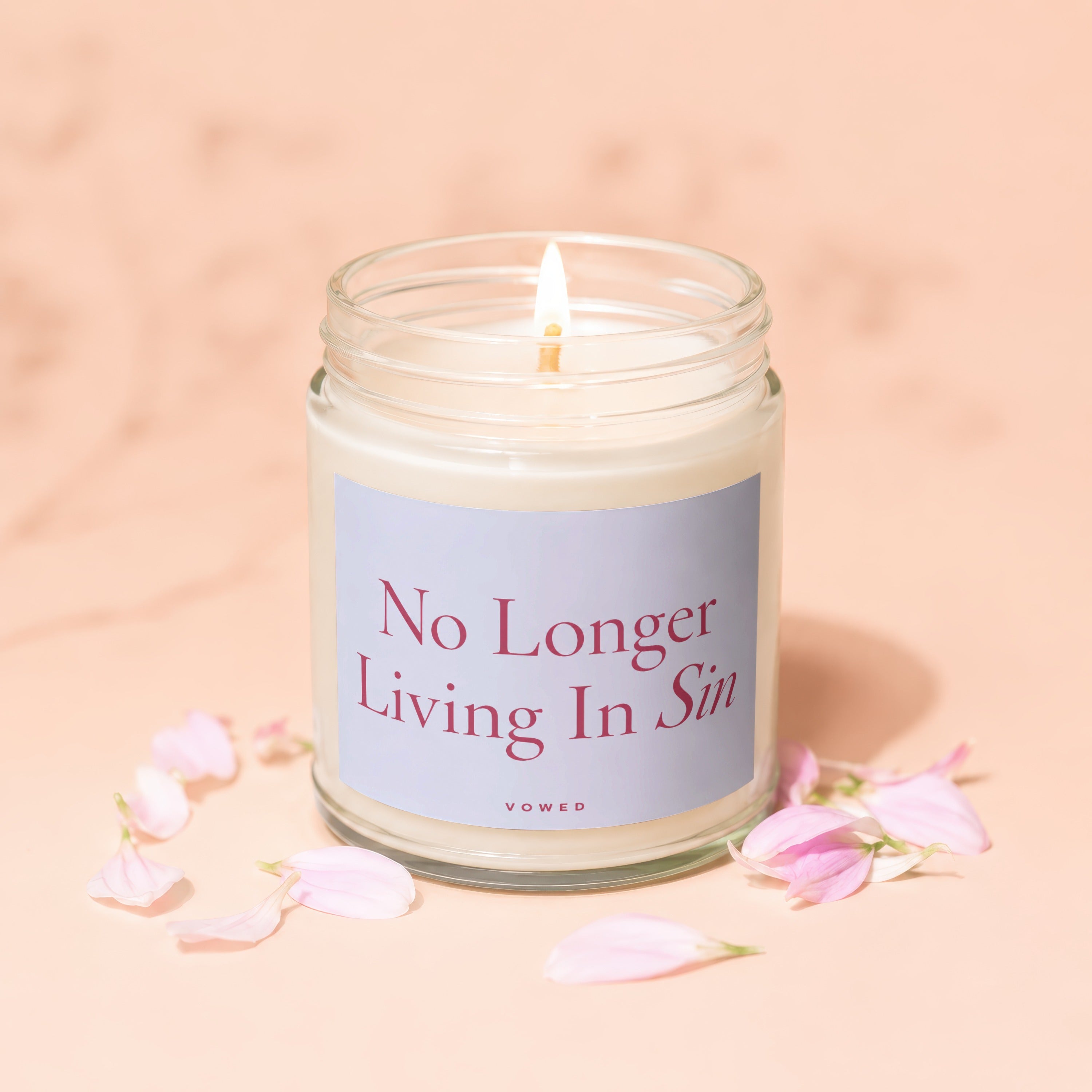 Glass jar candle with lit wick and "No Longer Living In Sin" text.