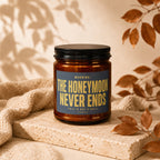 Amber jar candle with dark blue label reading "WARNING: THE HONEYMOON NEVER ENDS".