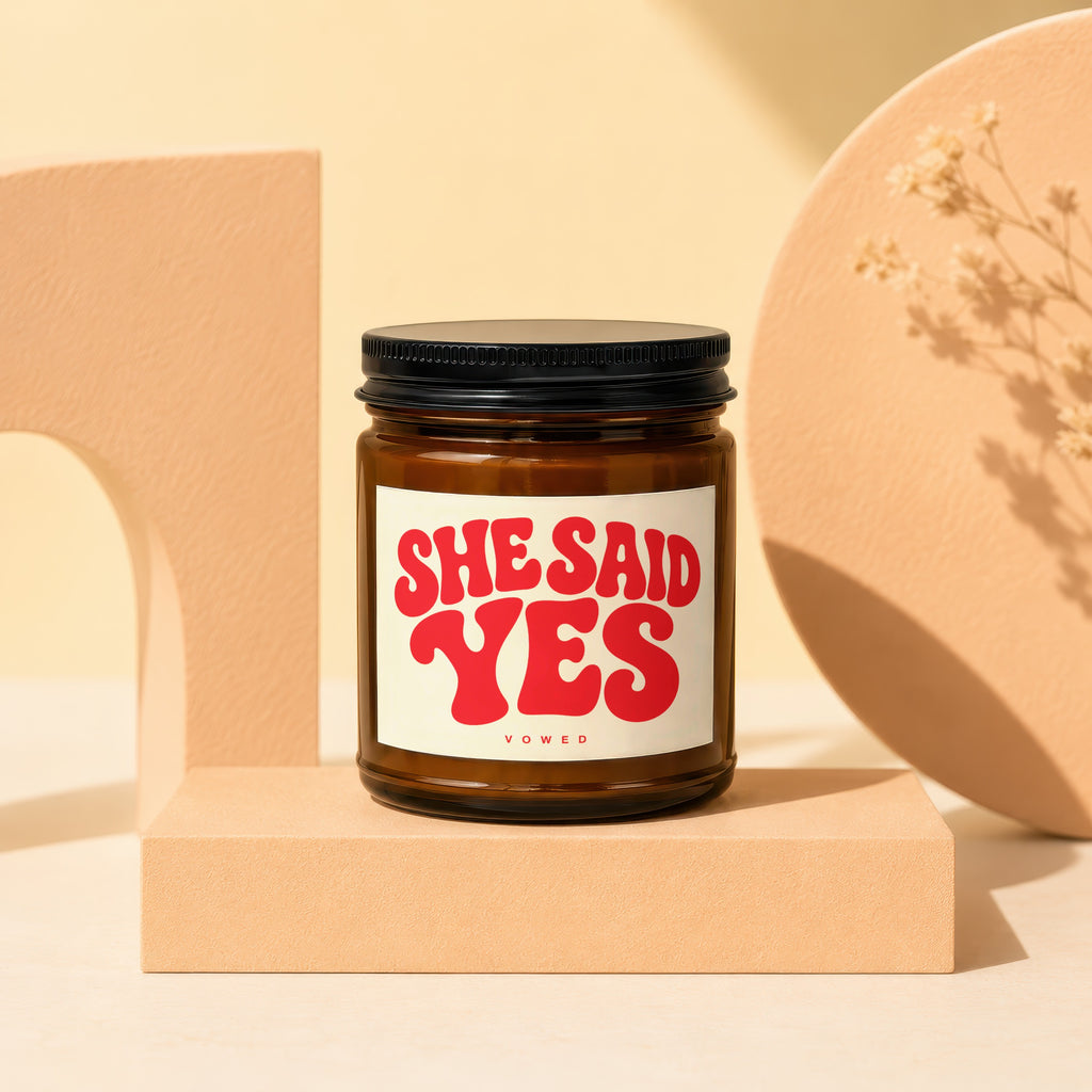Amber jar candle with red "She Said Yes" text on the label.