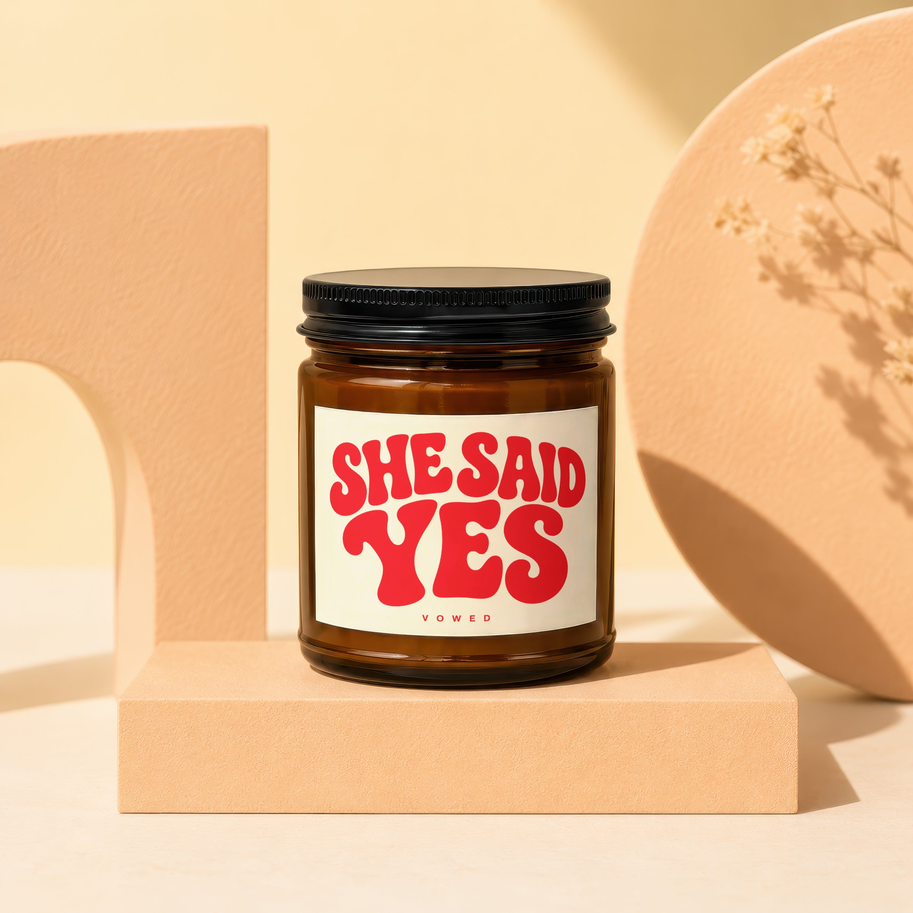 Amber jar candle with red "She Said Yes" text on the label.