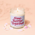 Candle with "Fine Better Together" text and pink flower petals on a peach background.