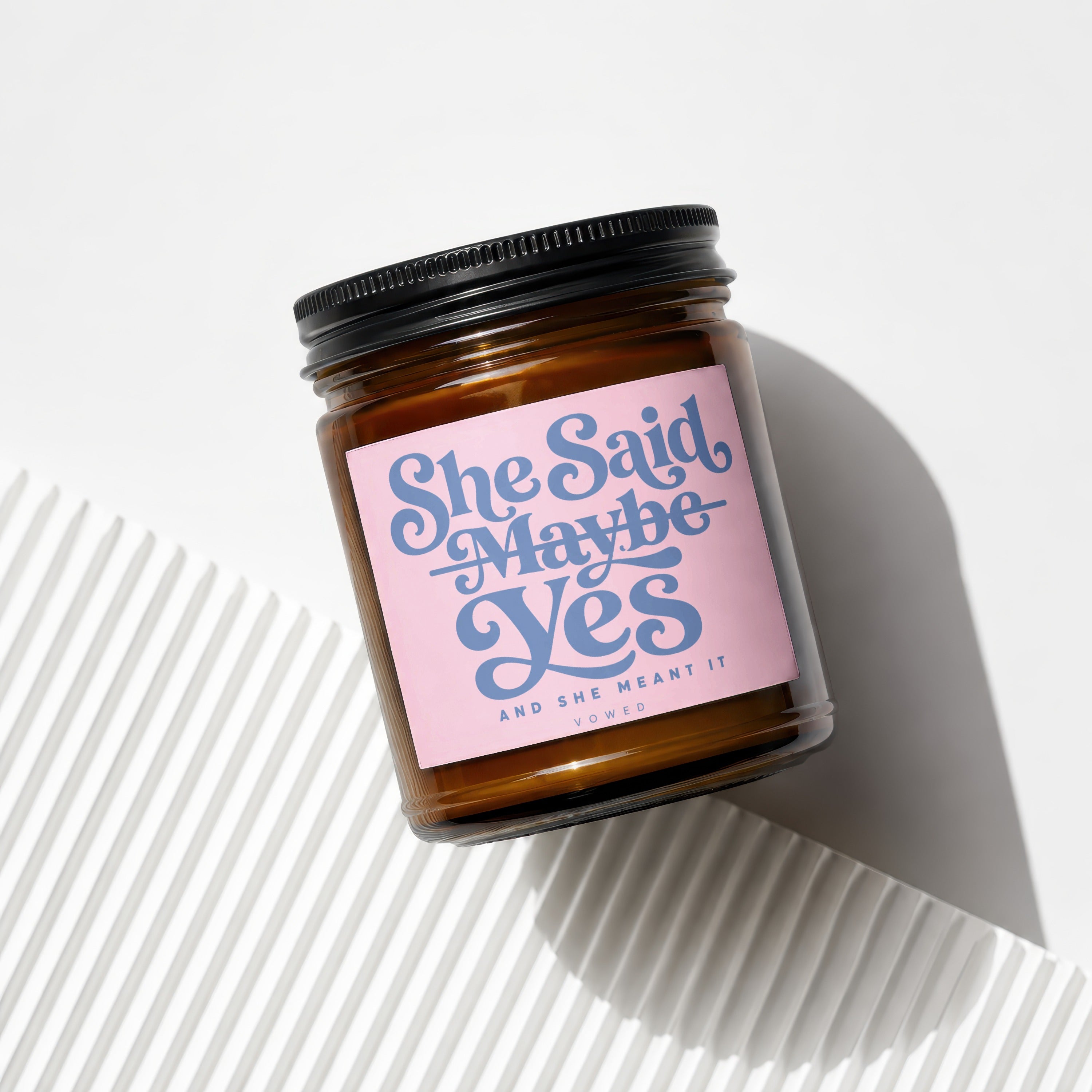 Brown glass candle with pink label reading "She Said Maybe Yes AND SHE MEANT IT".