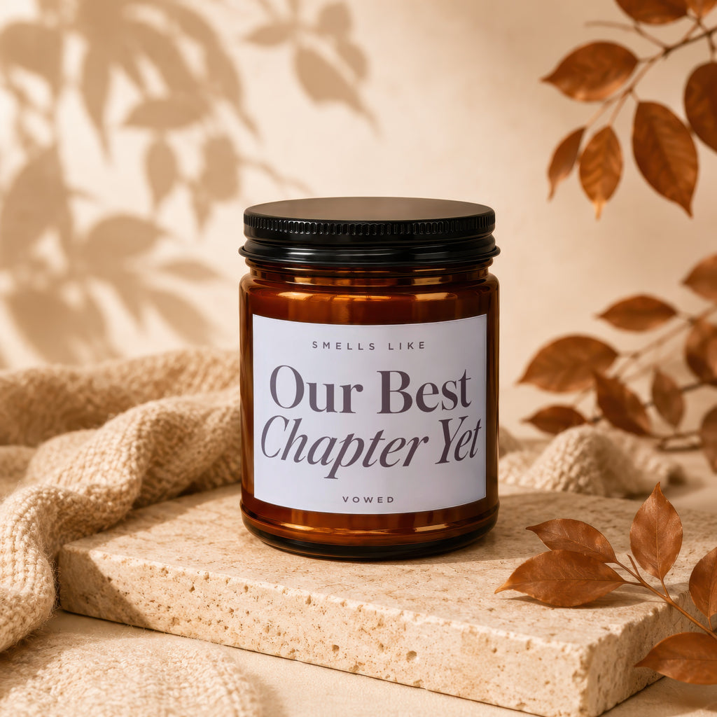 Brown glass candle with black lid and white label saying "Our Best Chapter Yet".