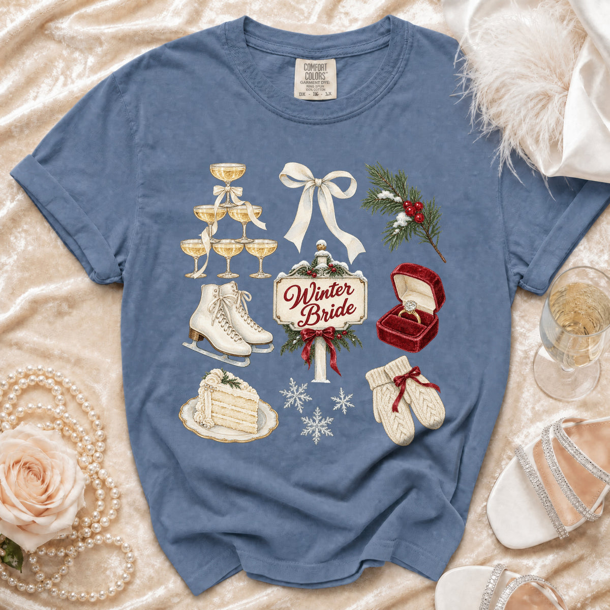 Blue t-shirt with winter bride graphic including champagne, cake, skates, and snowflakes.