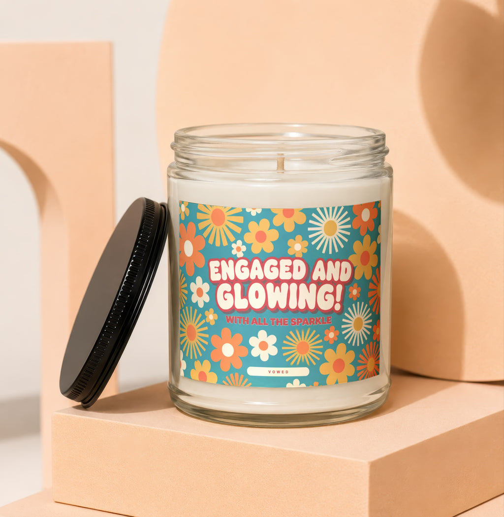 Candle with label saying "ENGAGED AND GLOWING! WITH ALL THE SPARKLE" on floral background.